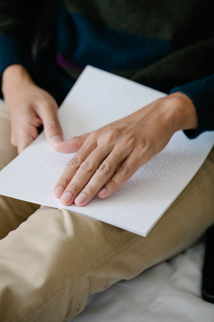Close-up of a person reading embossed braille text with fingers for tactile learning.