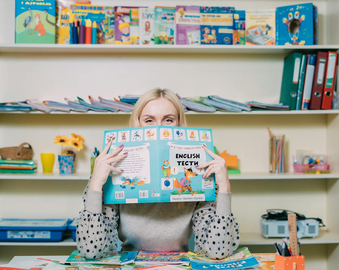 Woman reading an English book in a colorful classroom setting.